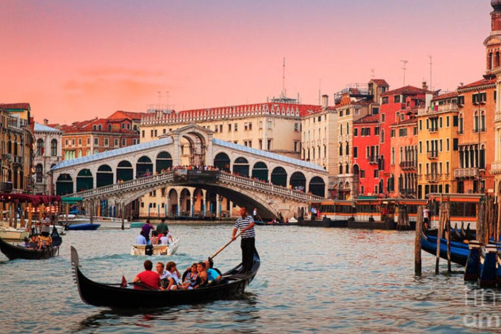 Gondola in front of Rialto bridge at dusk Venice Italy