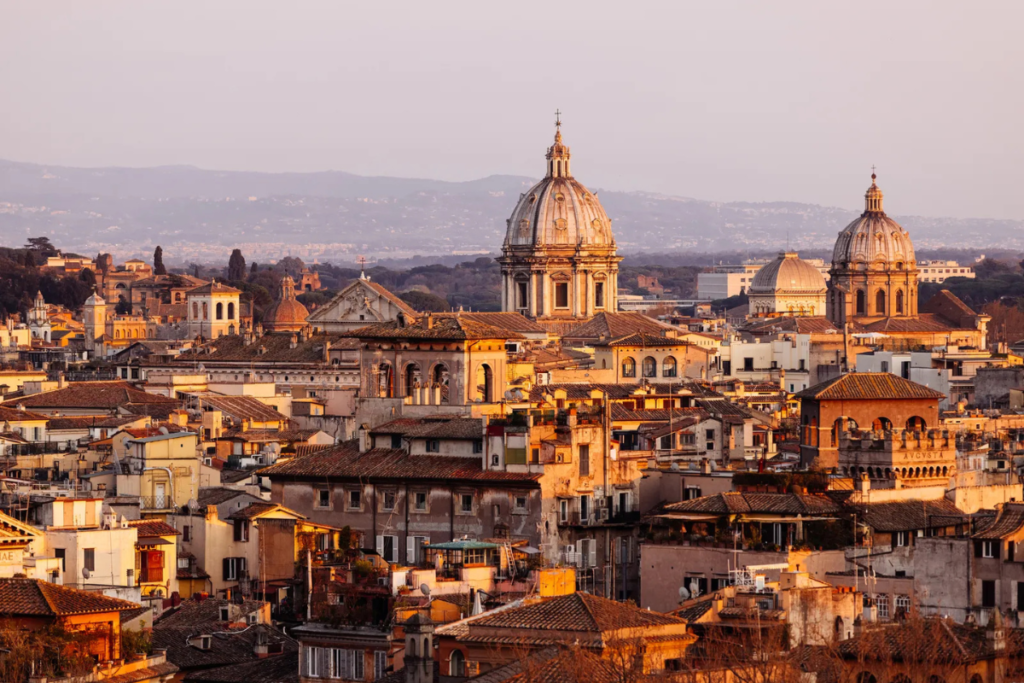 Scenic view of Rome’s historic rooftops and domes bathed in warm, golden sunset light.