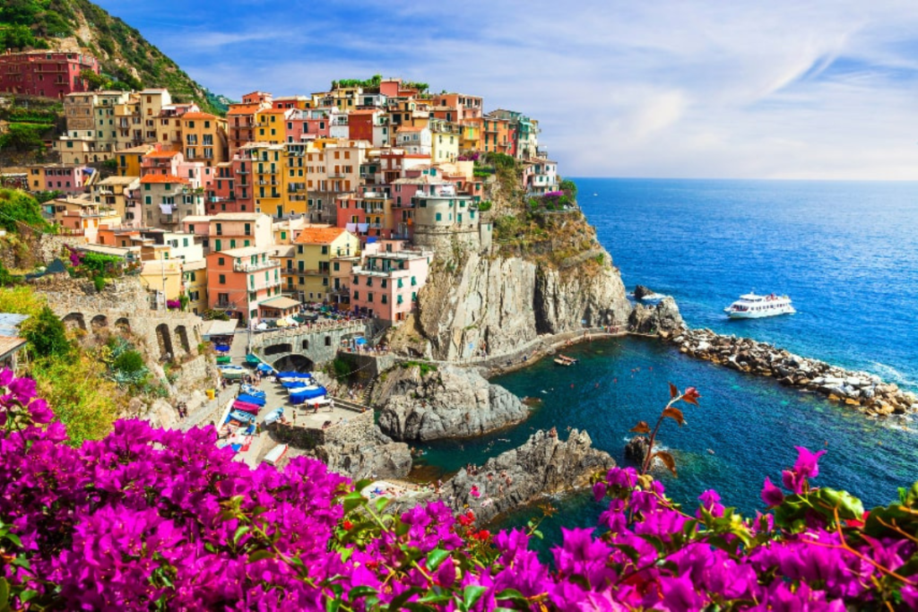 Colorful coastal village of Manarola in Cinque Terre with vibrant flowers and clear blue sea.