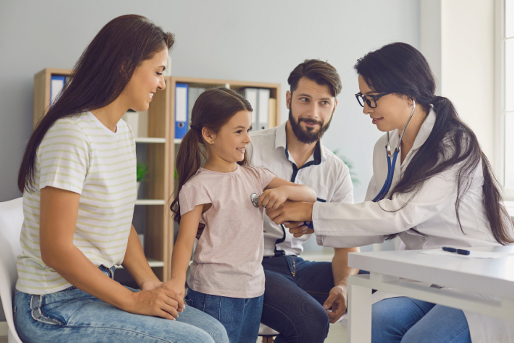 Doctor examines a young girl with her smiling parents present during a family medical checkup.