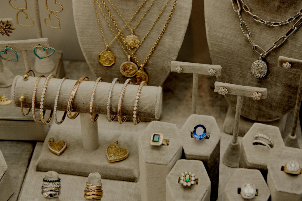 Display of luxurious jewelry, including gold necklaces, diamond bracelets, statement rings, and earrings on a velvet stand.